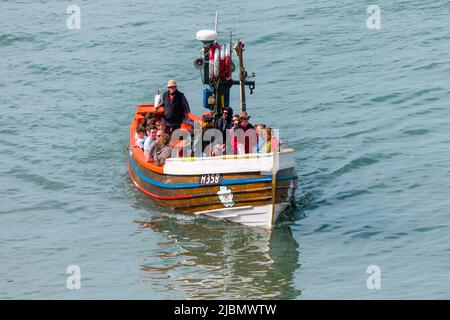 Touristes en mer sur un bateau de pêche traditionnel à coke de bois, Summer Rose H358, à Flamborough North Landing Banque D'Images