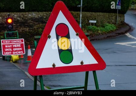 Un feu de signalisation temporaire avertissant des travaux de route à venir. Il y a 4 voies de contrôle de la circulation à une jonction de 4 routes à Baildon, Yorkshire. Banque D'Images