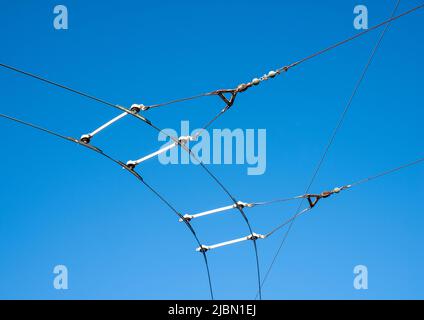 Câbles caténaires et de contact aériens pour un système de bus à chariot électrique sur une courbe avec un fond ciel bleu Uni. Banque D'Images