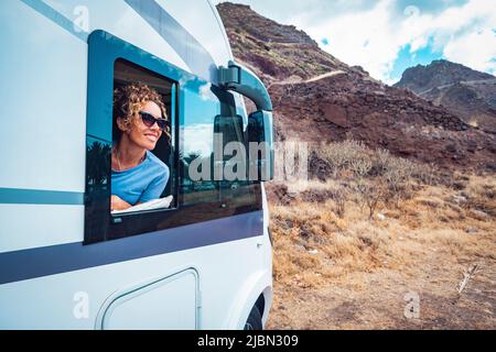 Bonne femme adulte sourire et profiter de la destination de voyage à l'intérieur de sa camionnette de camping. Les femmes gaies aiment voyager avec une camionnette de camping. Concept de la vie de la fourgonnette a Banque D'Images