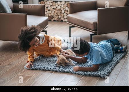 Les enfants sont couchés sur le sol à côté de leur animal de compagnie et ont l'air heureux Banque D'Images