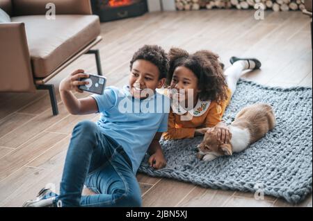 Un garçon en tshirt bleu faisant le selfie avec sa sœur et un chien Banque D'Images