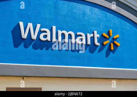 Façade extérieure de Walmart affichant la marque et le logo en lettres blanches avec un logo jaune sur fond bleu brillant lors d'une journée ensoleillée à Charlotte. Banque D'Images