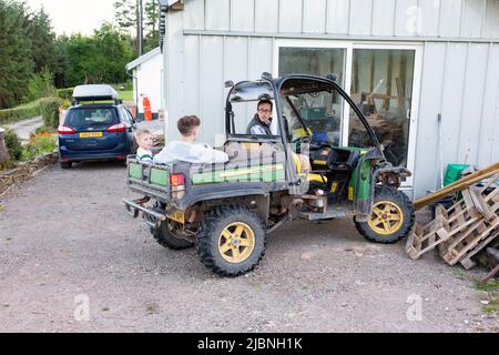 Garçons dans un véhicule utilitaire John Deere Gator, High Bickington, Devon, Angleterre, Royaume-Uni. Banque D'Images