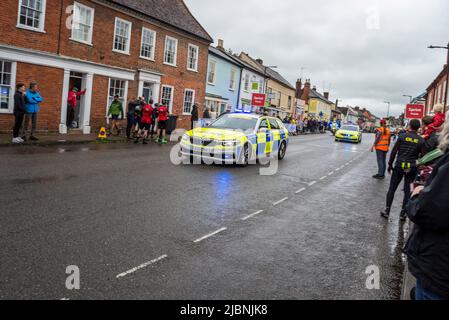 Des véhicules de police qui soutiennent la course cycliste UCI Women’s Tour, étape 1, qui traverse High Street, Hadleigh, Suffolk. Route mouillée par la pluie Banque D'Images