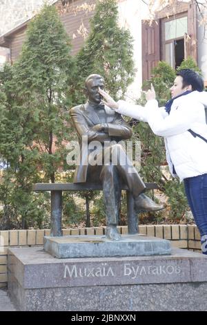 Lady touche le nez du monument Mikhail Boulgakov près de sa maison-musée à Kiev. C'est comme une bonne chance doit faire lors de la visite de ' Maître et Marguerite' auteur Banque D'Images