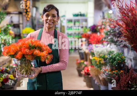 Une fleuriste latino-américaine souriante se dresse avec des fleurs Banque D'Images