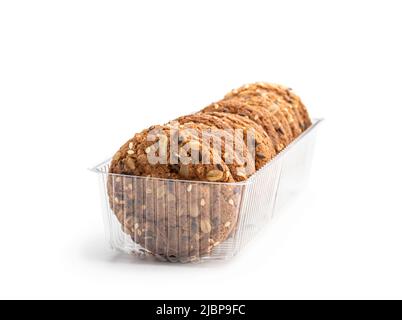 Biscuits d'avoine sains avec différentes graines dans un emballage en plastique isolé sur blanc Banque D'Images