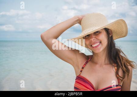 NUNGWI, Zanzibar, Tanzanie: Portrait d'une femme souriant à l'appareil photo, portant un chapeau de soleil à la plage Banque D'Images