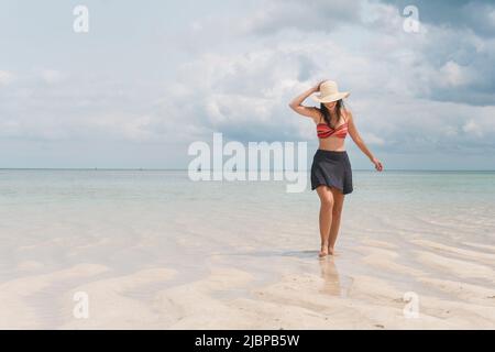 NUNGWI, Zanzibar, Tanzanie: Femme portant un chapeau de soleil marchant sur la plage à marée basse. Banque D'Images