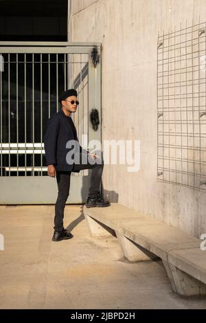 Latino gay mâle avec maquillage portant chapeau de mode posant dans la rue Banque D'Images