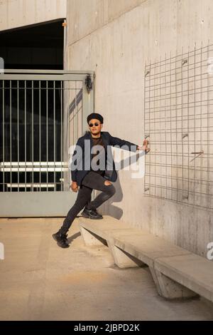 Latino gay mâle avec maquillage portant chapeau de mode posant dans la rue Banque D'Images