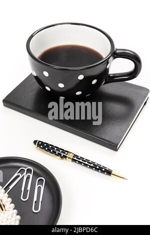 Espace de travail noir et blanc avec un mug à pois et un cahier Banque D'Images