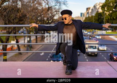 Latino gay mâle avec maquillage portant chapeau tendance posé sur un pont Banque D'Images