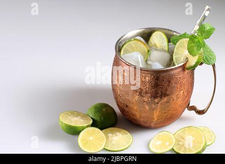 Moscou Mule Ice Cold cocktail en cuivre Cup avec fond de table blanc citron et menthe, espace de copie pour le texte Banque D'Images