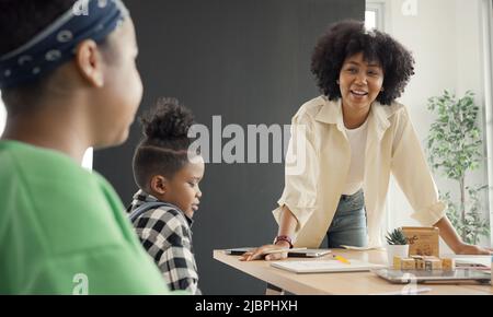 Salle de classe avec divers apprenants de heureusement des étudiants afro-américains et des enseignants faisant des activités ensemble. L'enseignant enseigne, guide et talki Banque D'Images