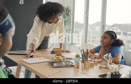 Salle de classe avec divers apprenants de heureusement des étudiants afro-américains et des enseignants faisant des activités ensemble. L'enseignant enseigne, guide et talki Banque D'Images