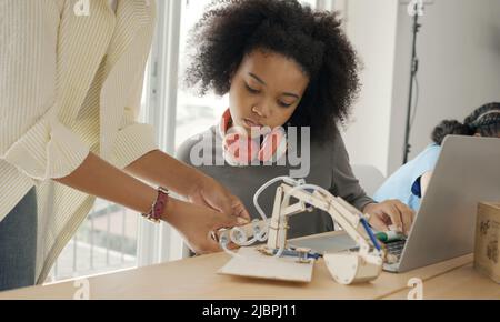 Salle de classe avec divers apprenants de heureusement des étudiants afro-américains et des enseignants faisant des activités ensemble. L'enseignant enseigne, guide et talki Banque D'Images