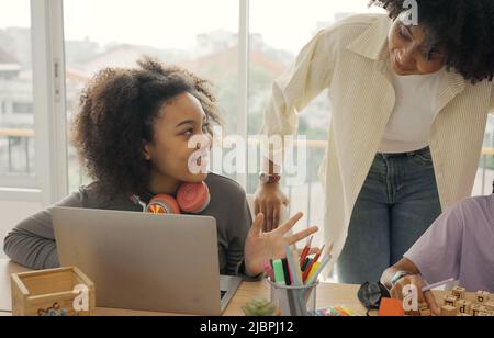 Salle de classe avec divers apprenants de heureusement des étudiants afro-américains et des enseignants faisant des activités ensemble. L'enseignant enseigne, guide et talki Banque D'Images