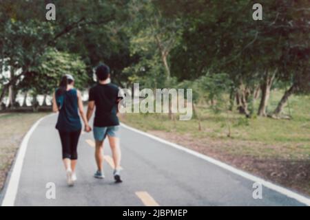 Concept flou de couple en amoureux tenant les mains exercice de marche dans le parc. Banque D'Images