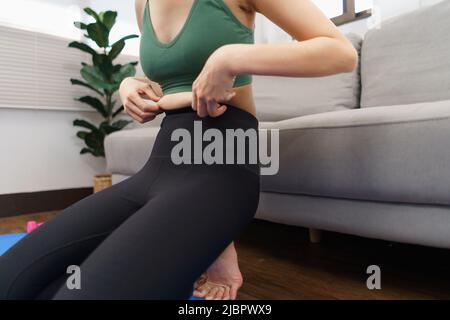 Concept de perte de poids et de santé, jeune femme asiatique utilise sa main pour tenir le ventre gras excessif. Banque D'Images