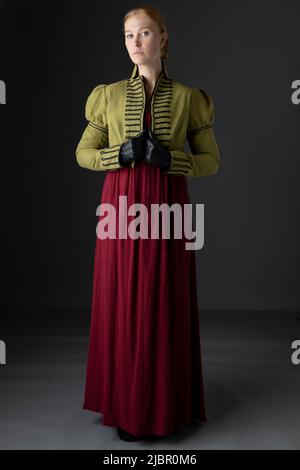 Femme Régence portant un linge vert spencer et une robe rouge sur fond de studio Banque D'Images