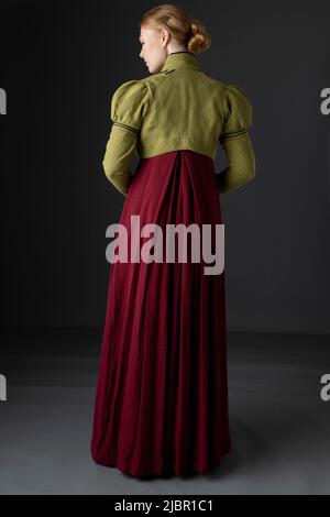 Femme Régence portant un linge vert spencer et une robe rouge sur fond de studio Banque D'Images