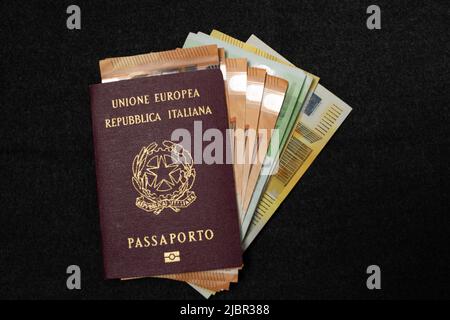 Passeport italien rempli de billets en euros sur fond sombre. ID de voyage et argent comptant. Fonds de voyage, cinquante, cent deux cents euros pour Europ Banque D'Images