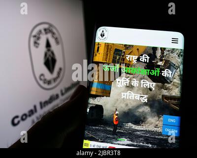 Personne tenant un téléphone portable avec la page Web de la société minière Coal India Limited (CIL) sur l'écran devant le logo. Concentrez-vous sur le centre de l'écran du téléphone. Banque D'Images