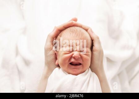 Maman tient doucement un nouveau-né dans ses paumes. Les premiers jours de la vie, les émotions des enfants Banque D'Images