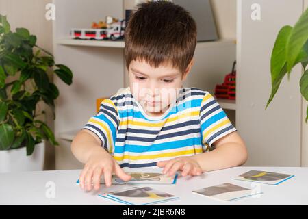 Un garçon de 4 ans rassemble une photo d'un raton laveur à partir de puzzles tout en étant assis à la table. Banque D'Images