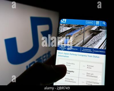 Personne tenant un smartphone avec la page Web de la société japonaise West Japan Railway (JR) à l'écran devant le logo. Concentrez-vous sur le centre de l'écran du téléphone. Banque D'Images