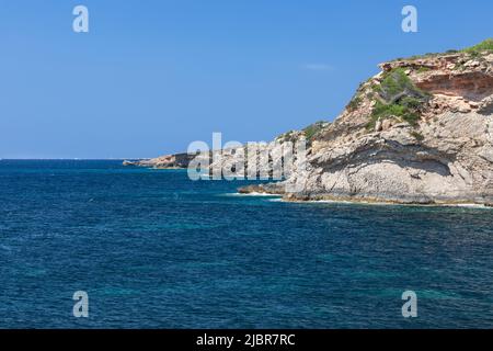 Côte rocheuse de l'île d'Ibiza brûlée par le soleil d'été avec une végétation clairsemée, mer calme et paisible, jour clair, pas un nuage dans le ciel, Iles Baléares, Banque D'Images