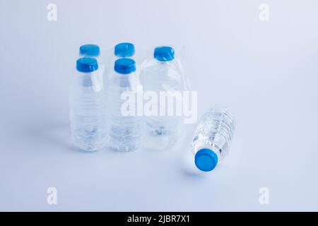 Six petites bouteilles en plastique d'eau de source naturelle sur fond blanc. L'une d'entre elles est couchée. Banque D'Images