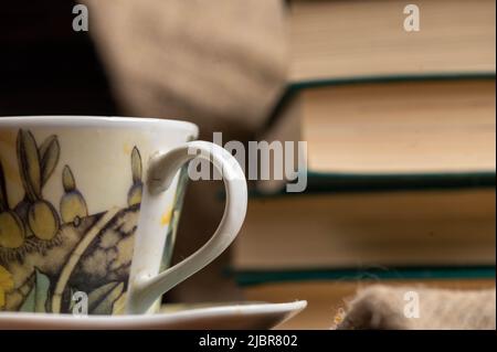 Une tasse de thé fort sur une soucoupe et une pile de livres sur la table. Banque D'Images