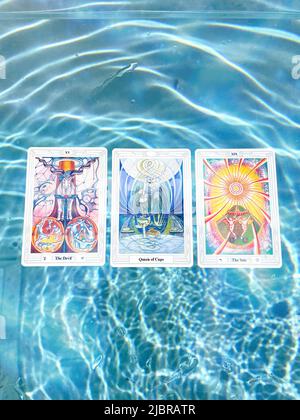 Thoth Astrologie Tarot Card Deck s'étend flottant dans la piscine bleue d'été avec des flambeaux. Banque D'Images