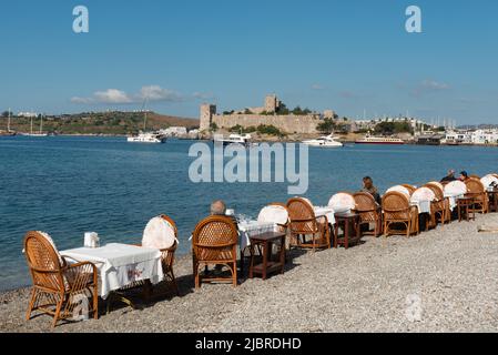 Bodrum, Mugla, Turquie. Restaurant 21 avril 2022 tables sur la plage dans le port de Bodrum avec le château de Bodrum en arrière-plan, la côte égéenne de sout Banque D'Images