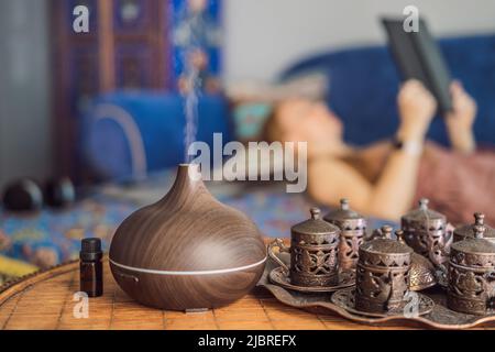 Concept d'aromathérapie. Diffuseur et humidificateur d'huile essentielle à ultrasons en bois électrique. Diffuseur d'arôme ultrasonique pour la maison. Femme se reposant à Banque D'Images