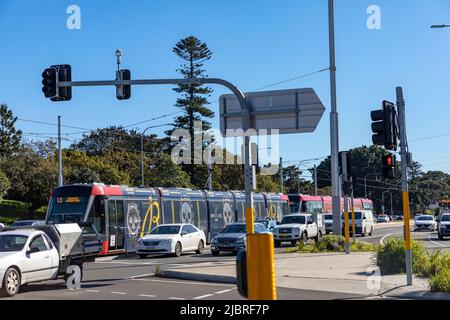 Train léger de Sydney sur la parade ANZAC à Sydney avec des voitures voyageant le long du réseau routier, Sydney, Australie Banque D'Images