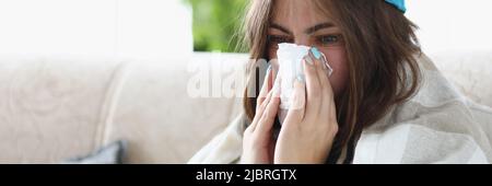 Une femme essuie le nez mouillé avec un mouchoir habillé de vêtements chauds à cause du froid Banque D'Images