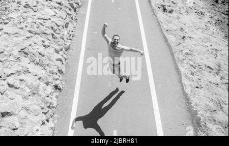 célébrant le succès. homme mûr sautant sur la route. plein d'énergie. gars heureux sentir la liberté. Banque D'Images