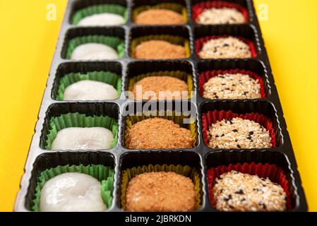 Bonbons japonais Mochi dans l'emballage d'usine sur fond jaune. Banque D'Images