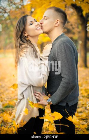 Baiser doux à la date d'un jeune couple dans le parc d'automne Banque D'Images