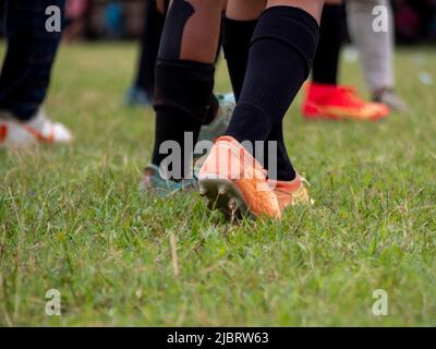 Joueur de football portant des chaussures de football marchant sur l'herbe avec une attention sélective. Banque D'Images