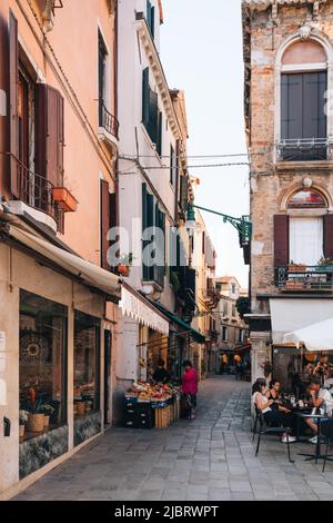 Venise, Italie - 21 mai 2022 : vue sur les magasins et les restaurants dans une rue étroite de Venise, capitale de la Vénétie et une destination de voyage célèbre. Banque D'Images