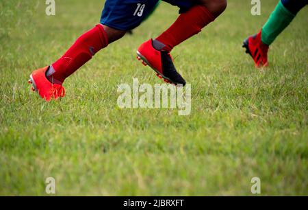 Joueur de football portant des chaussures de football marchant sur l'herbe avec une attention sélective. Banque D'Images