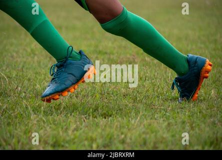 Joueur de football portant des chaussures de football marchant sur l'herbe avec une attention sélective. Banque D'Images