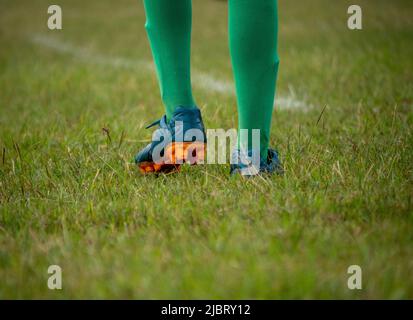 Joueur de football portant des chaussures de football marchant sur l'herbe avec une attention sélective. Banque D'Images