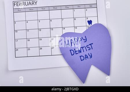 Bonne journée dentistes. Marque 9 février sur la clôture du calendrier. Carton en forme de dent avec texte. Banque D'Images