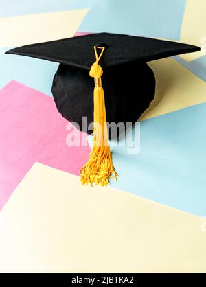 Casquette de remise de diplômes noire ou chapeau avec pampille jaune sur fond de couleur pastel éducation mortaboard Banque D'Images